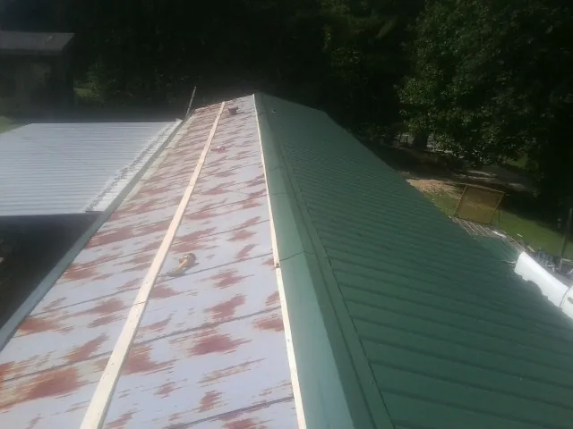 Old rusted panels beside newly installed green metal roofing — Wind Damage Roof Repair by Roofing Brothers in Powell