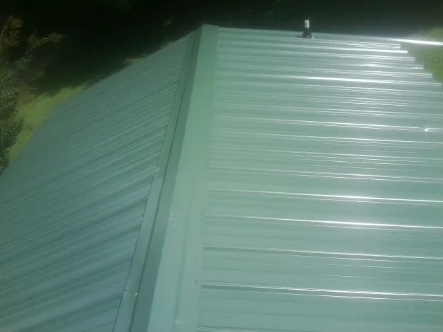 New green metal panels meeting at the ridge of a roof — Flat Roof Repair work by our crew in Powell