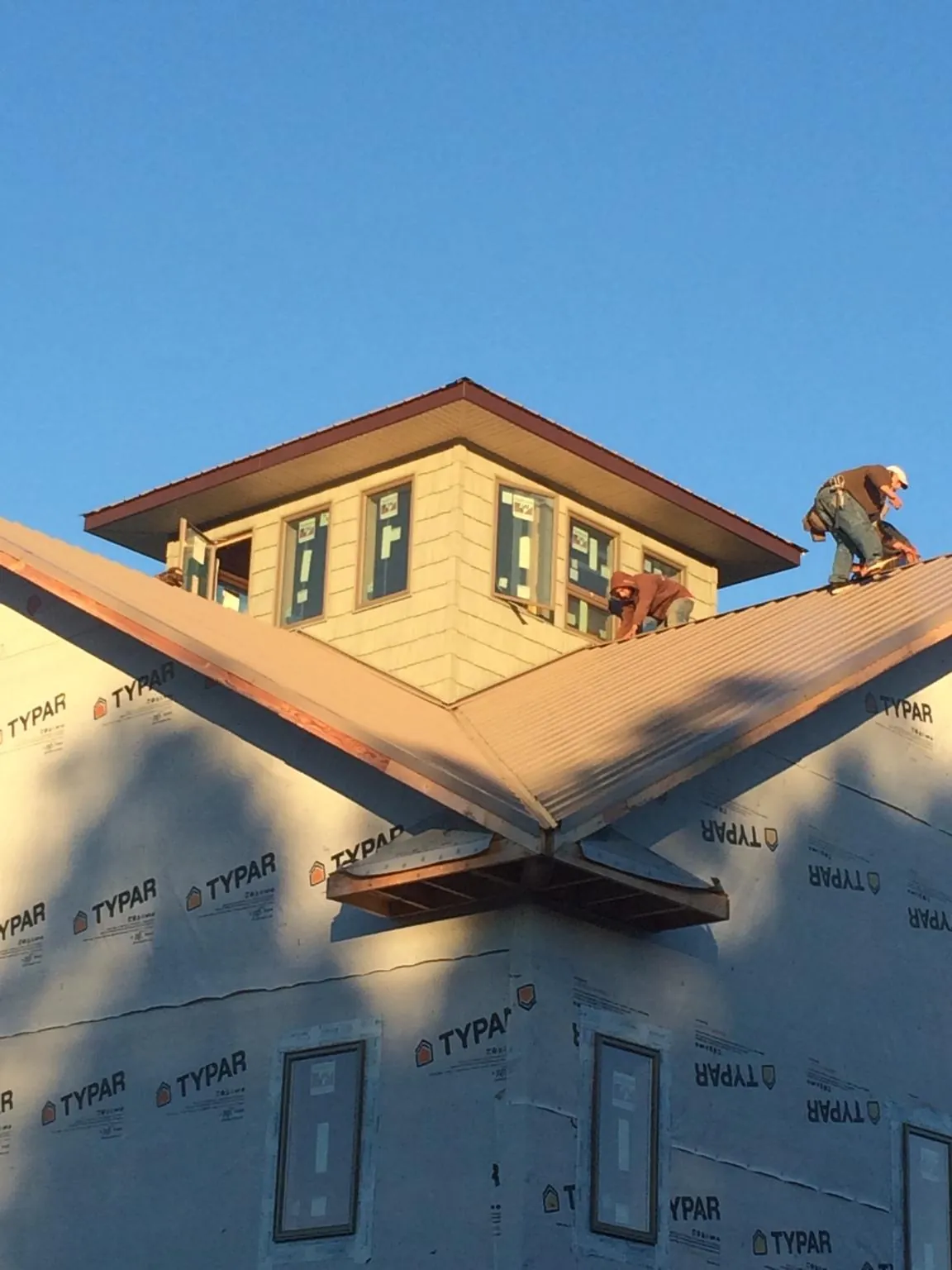 Roofers working around a rooftop cupola on a new metal roof at sunset — Roof Waterproofing in Powell by Roofing Brothers